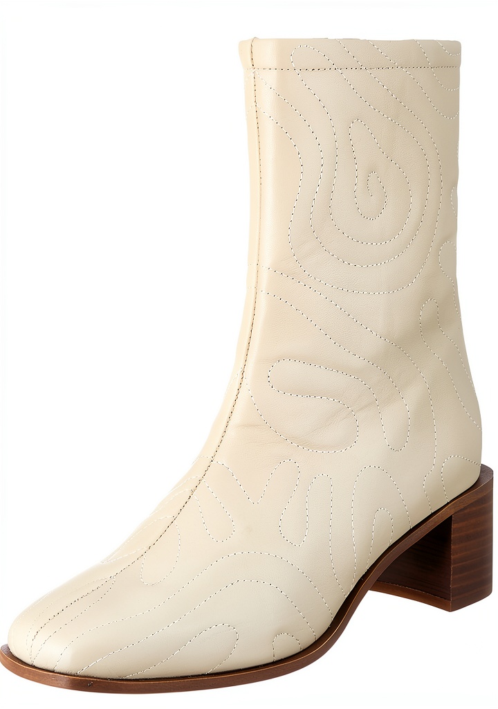 Donna che indossa stivali Scotch Soda Flora beige con gonna lunga e giacca trench in un parco autunnale
